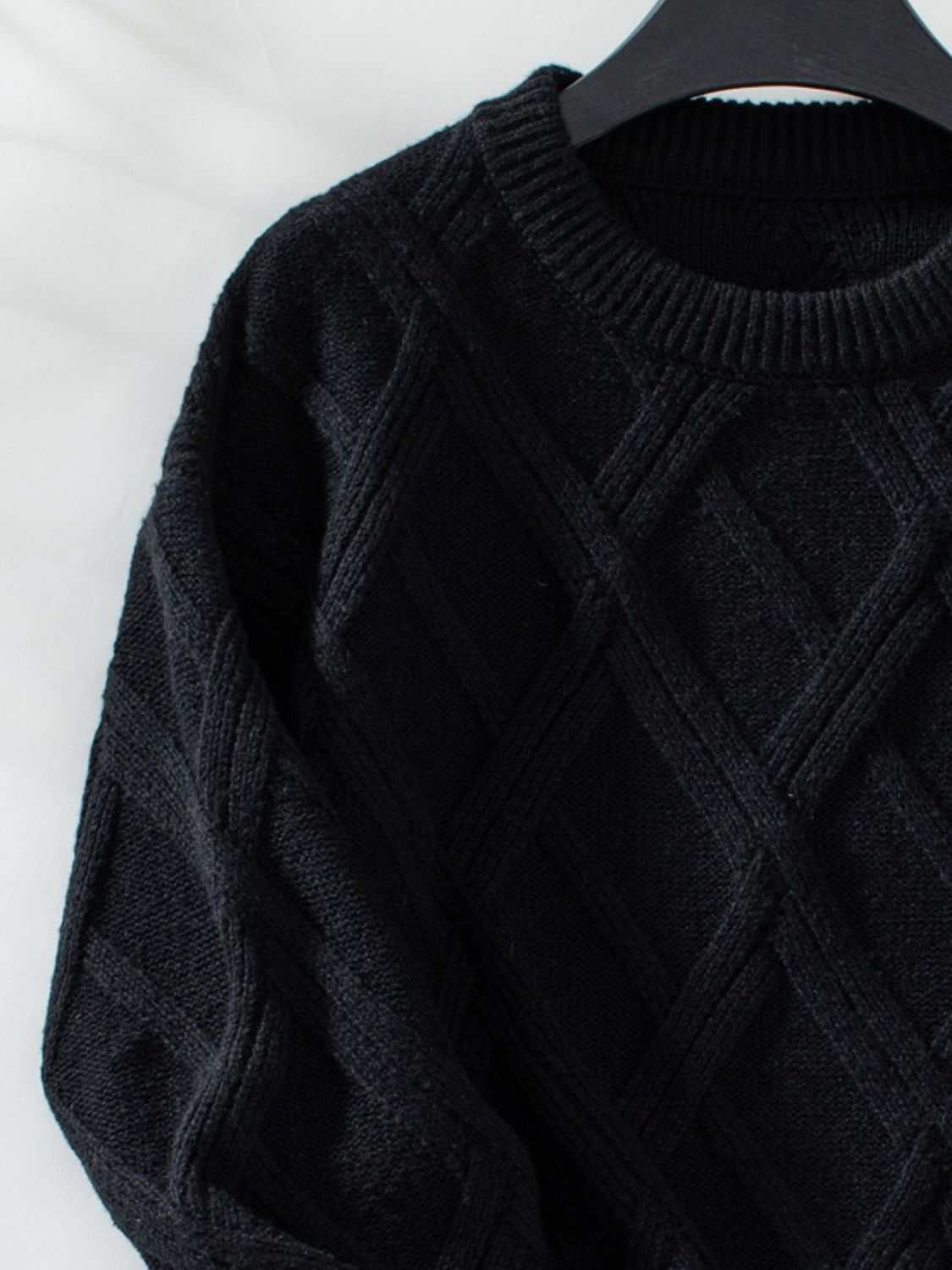 Black geometric round neck long sleeve sweater with textured pattern.