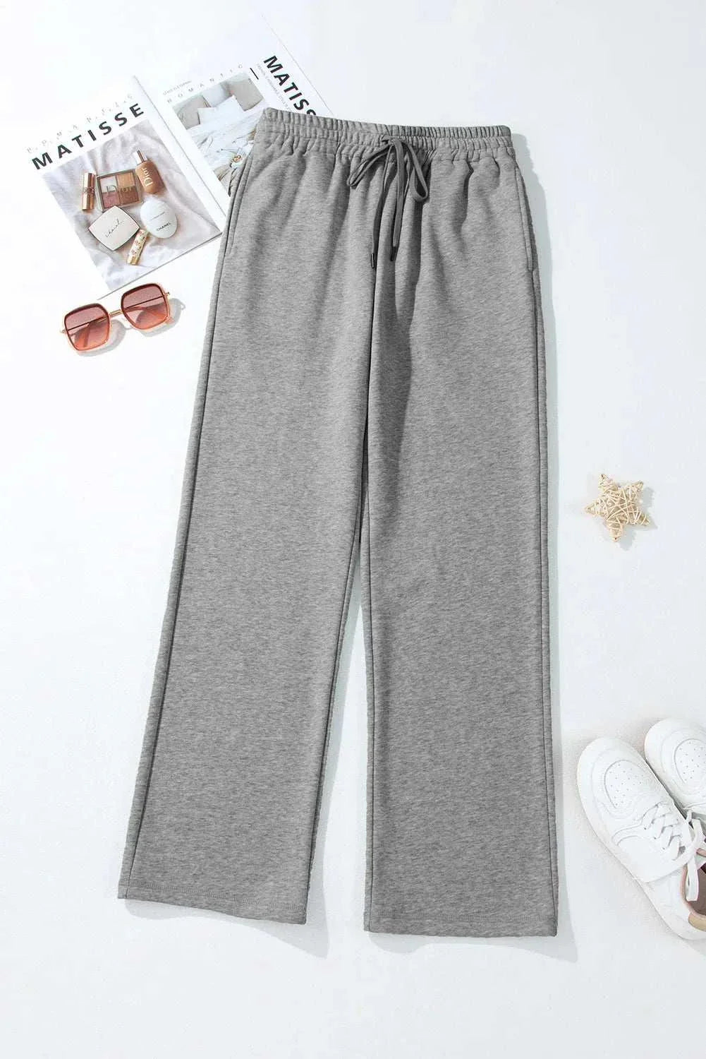 Gray drawstring pants with pockets made from polyester and cotton blend, displayed with accessories.
