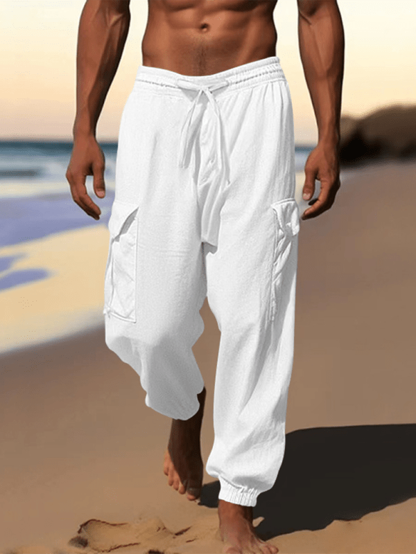 Casual cuffed multi-pocket drawstring trousers on a beach backdrop.