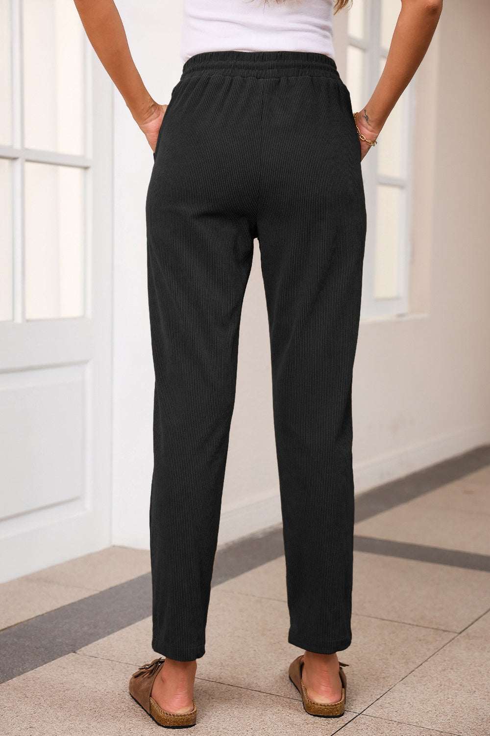 Drawstring straight pants with pockets in black, 100% polyester, back view.