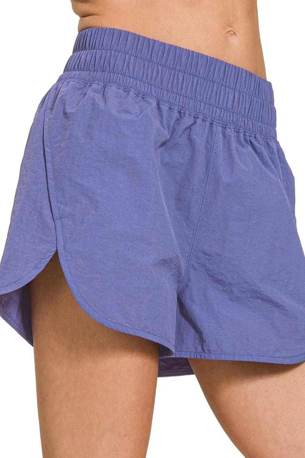 Windbreaker smocked waistband running shorts in purple with breathable, lightweight fabric and slit design.