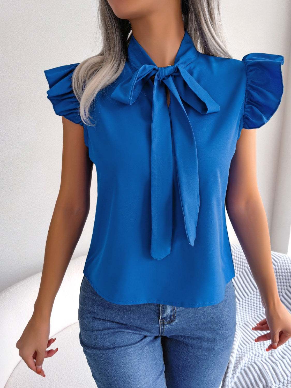 Tie neck cap sleeve blouse in blue with tied detail and slightly stretchy material.