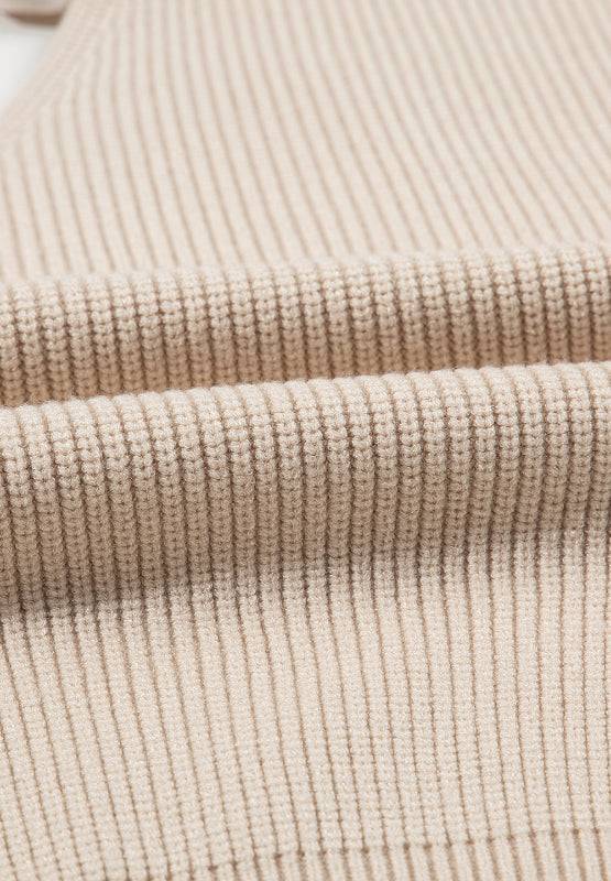 Close-up of ribbed fabric texture of a tied back V-neck long sleeve sweater in beige.