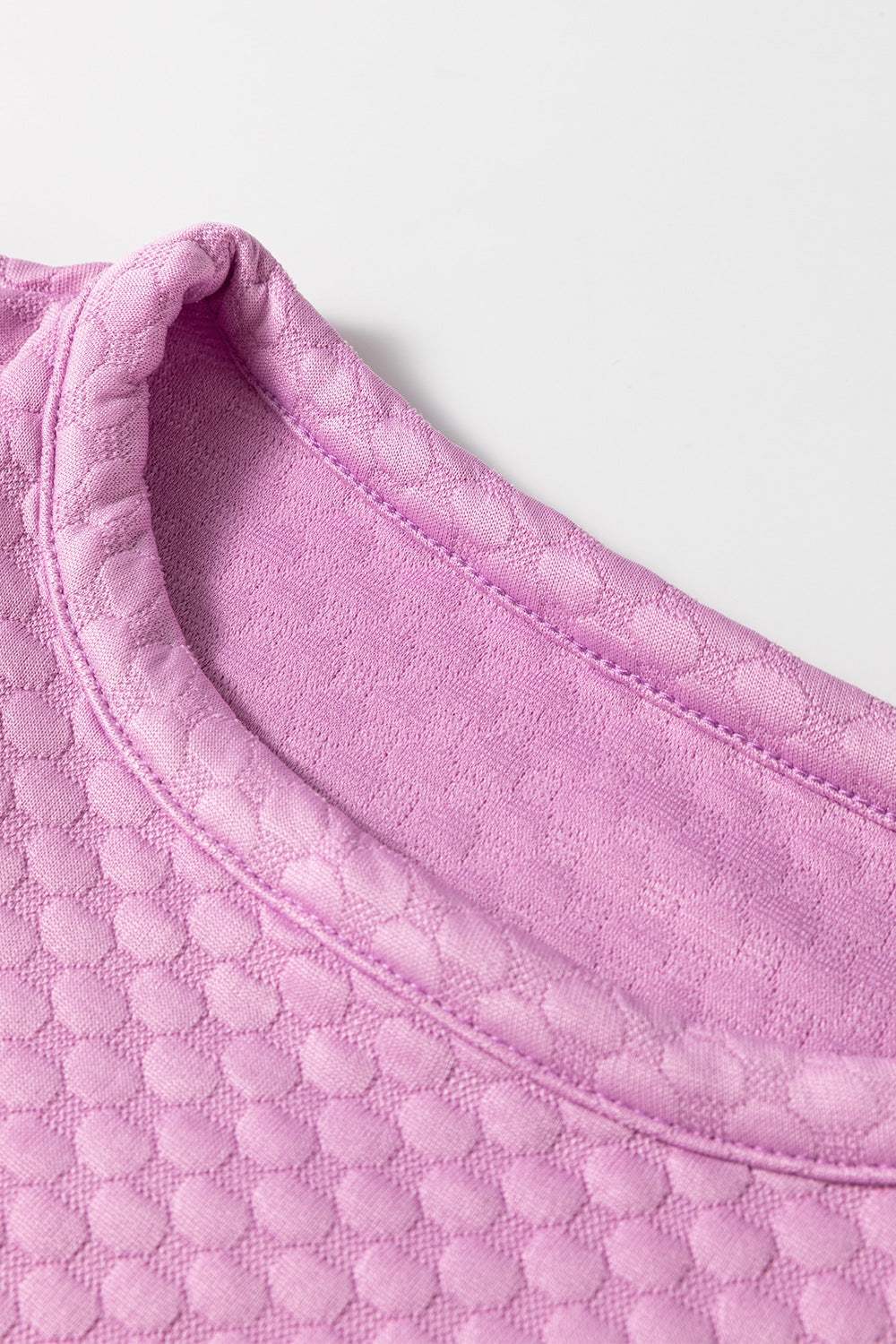 Textured round neck pink blouse with puff sleeves, showing detailed fabric pattern.