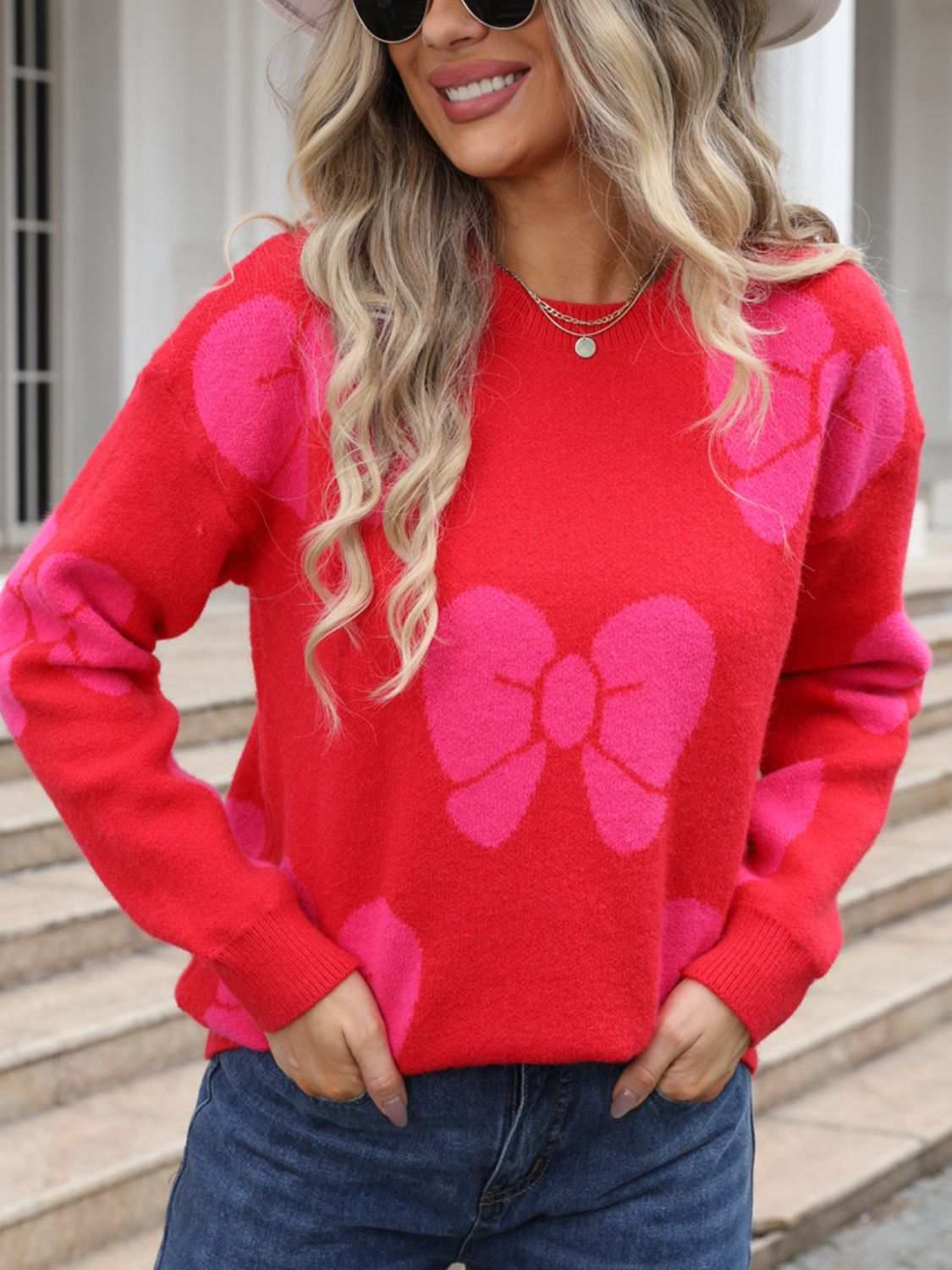 Red sweater with pink bow design, round neck, and dropped shoulders.