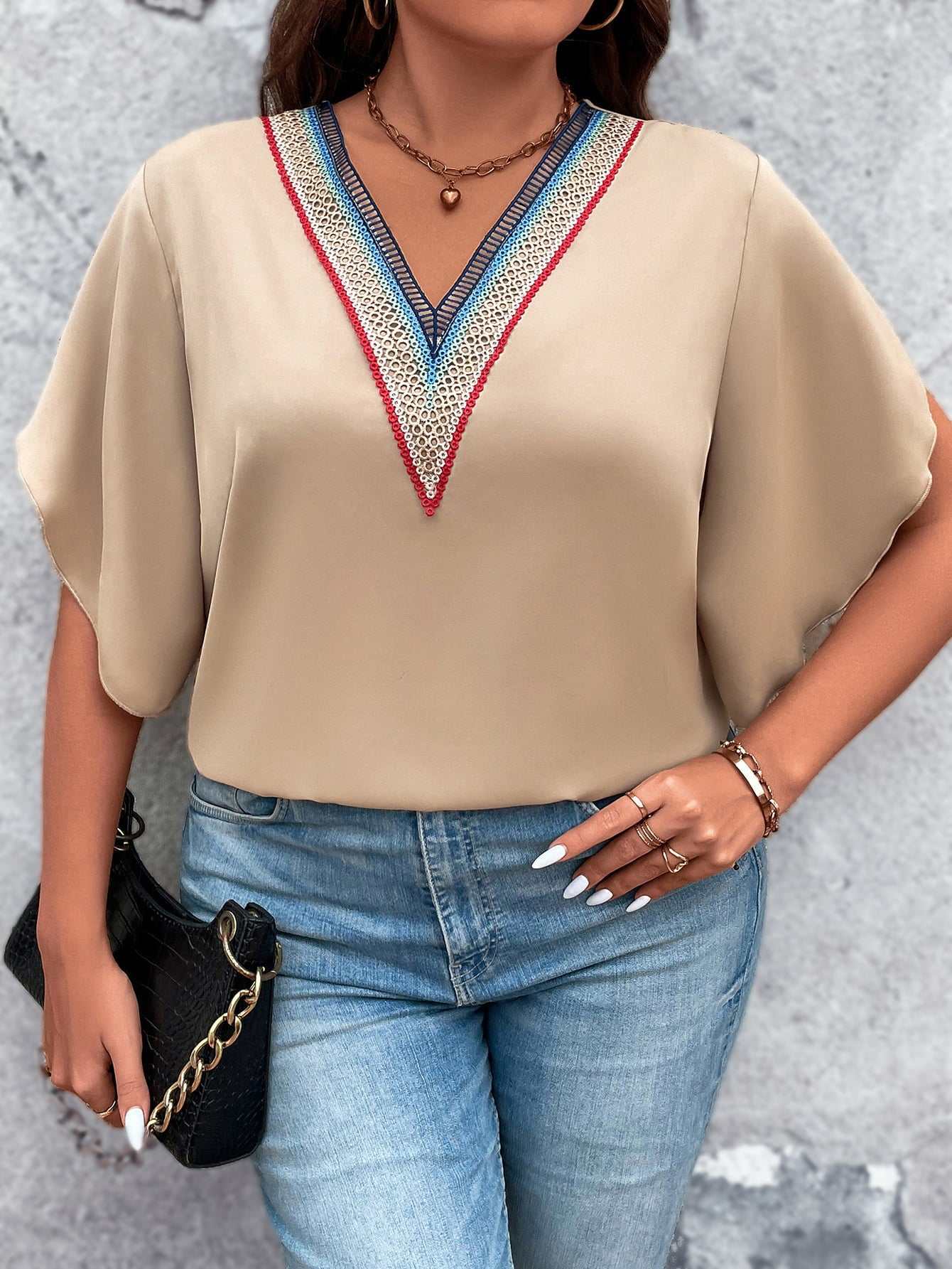 Plus size beige V-neck blouse with colorful contrast trim and flutter half sleeves paired with blue jeans