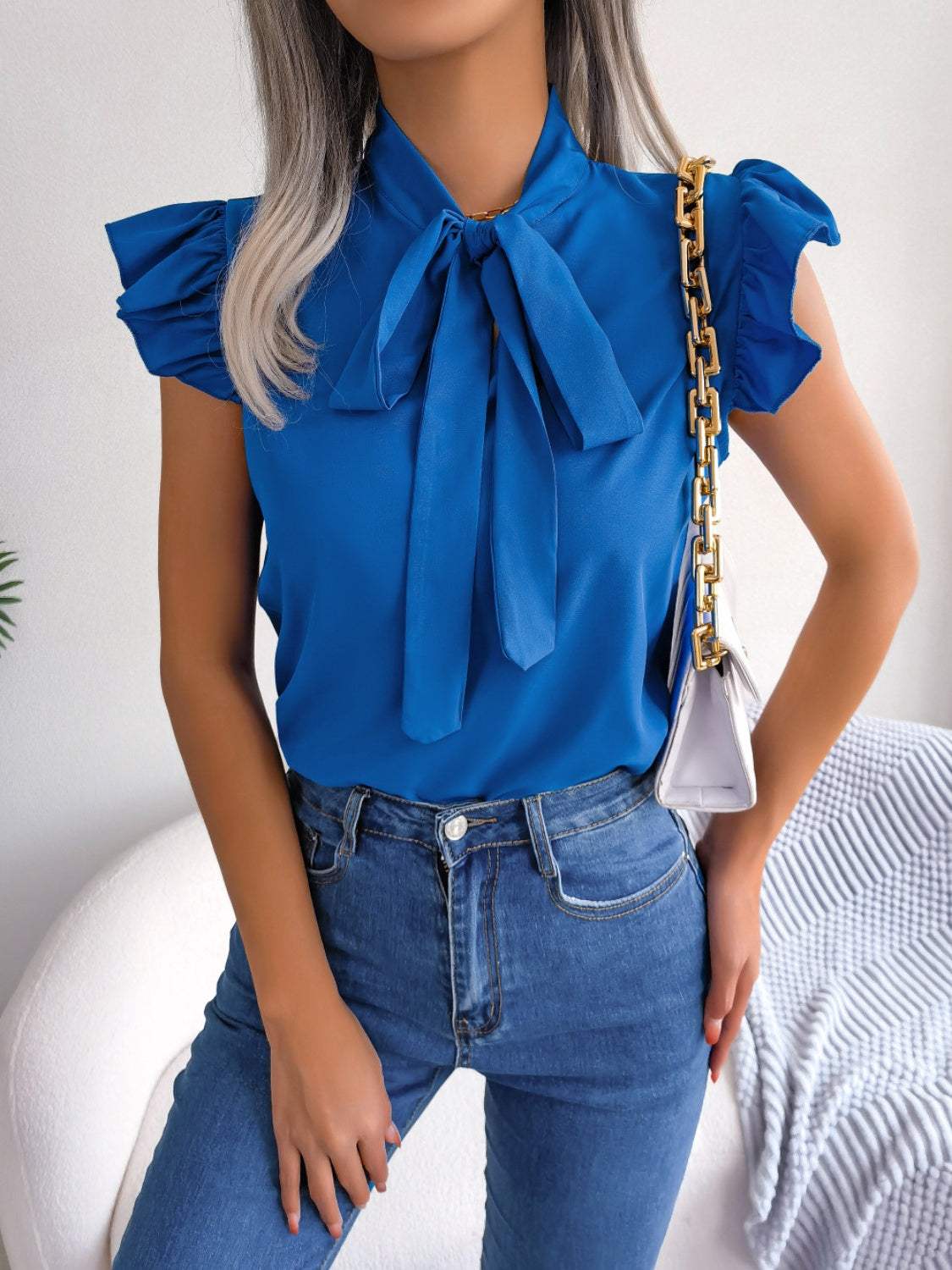 Blue tie neck cap sleeve blouse with slight stretch and tied features.