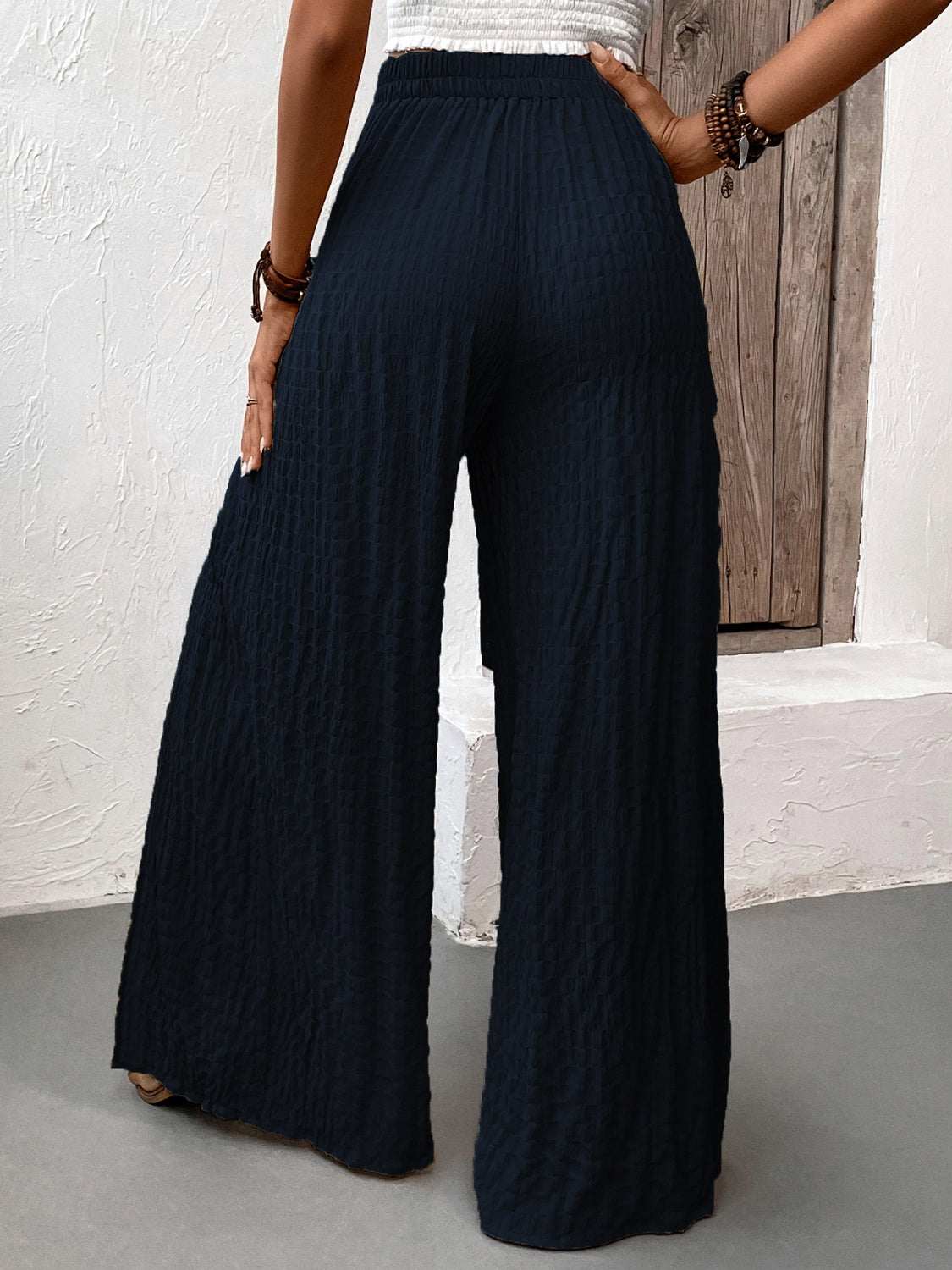 Honey Tied Slit Wide Leg Pants in black, featuring slits, made from polyester and elastane, shown from the back.