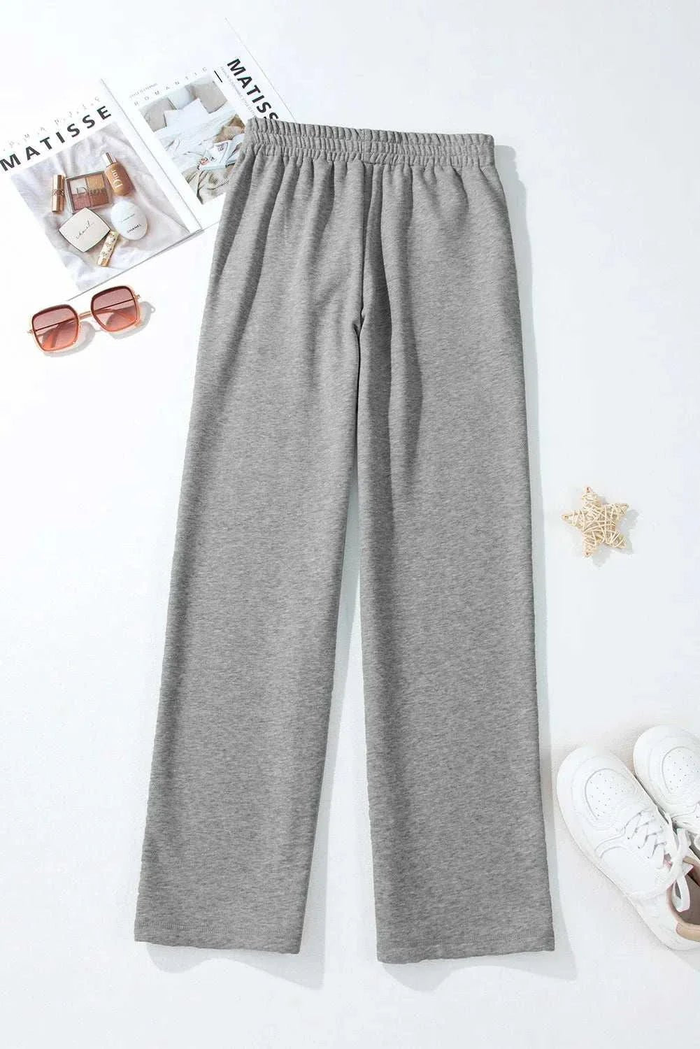 Gray drawstring pants with pockets made of polyester and cotton, displayed with accessories.