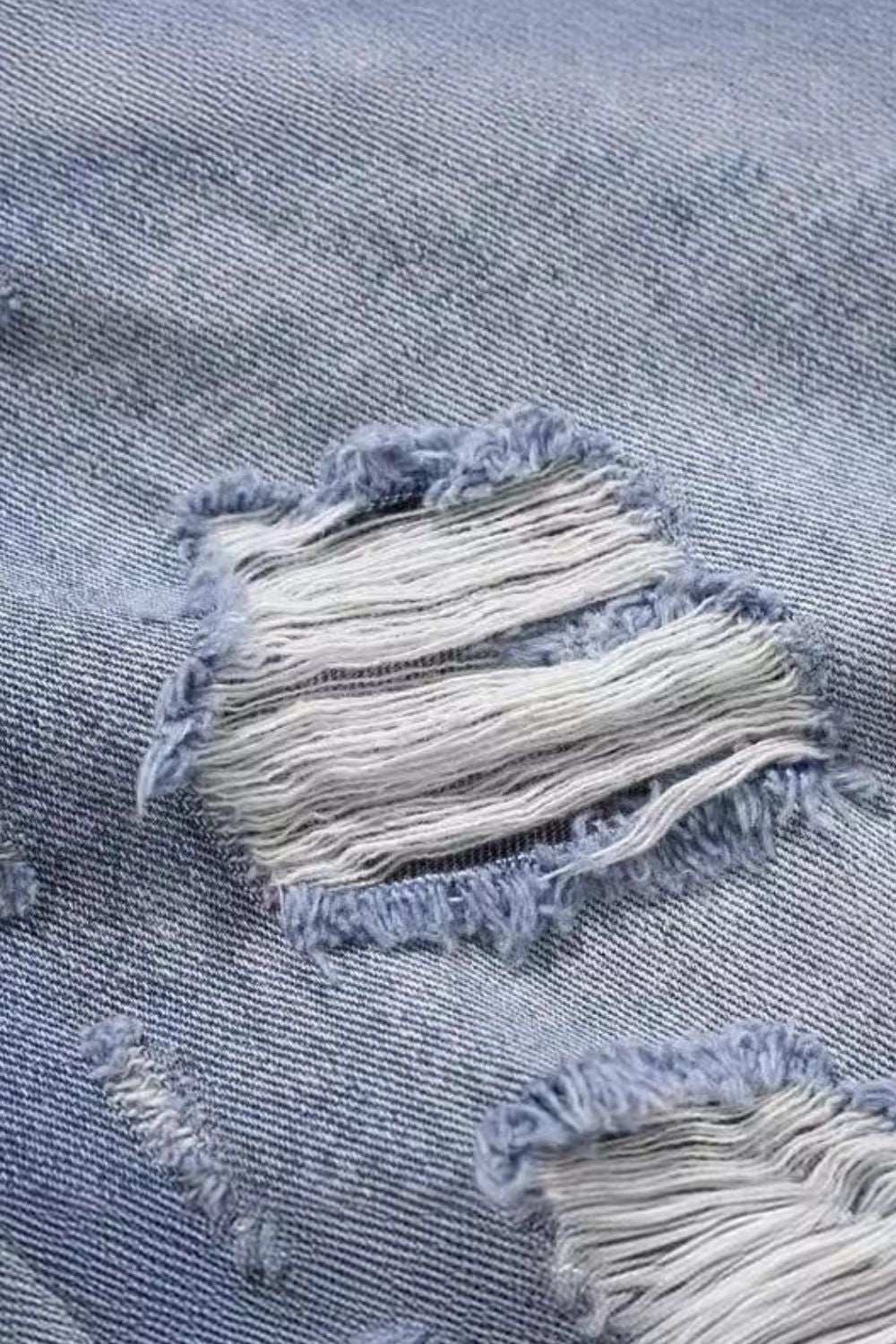 Men's distressed denim close-up with ripped detail.