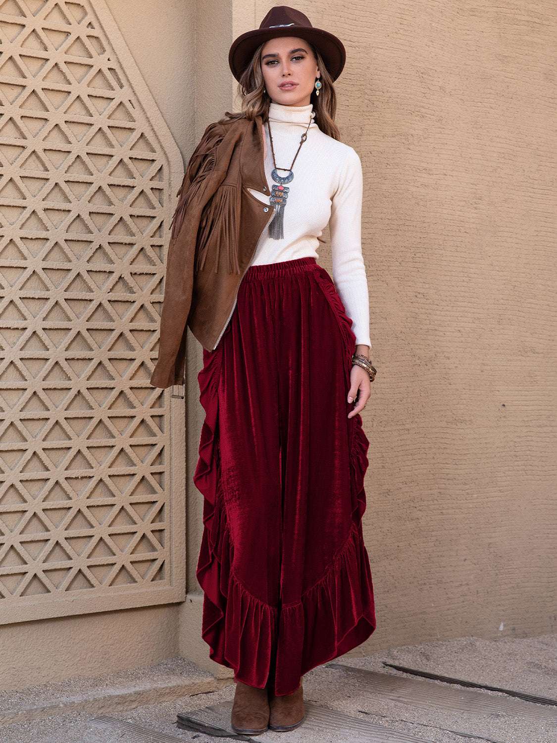 Woman wearing slit ruffled wide leg pants in red with a white turtleneck and brown accessories.