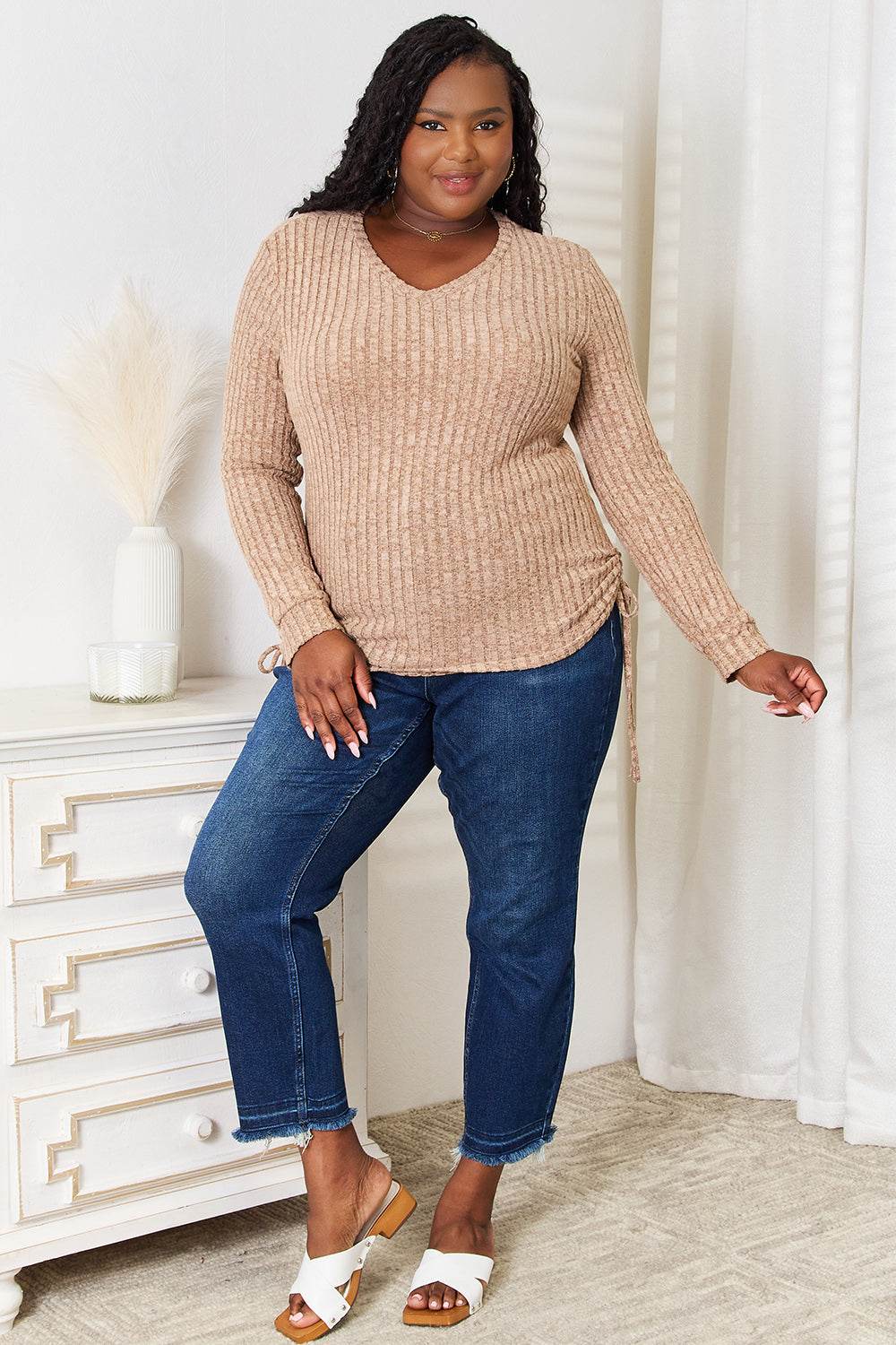 Curve model wearing a drawstring ribbed long sleeve t-shirt in beige with jeans.