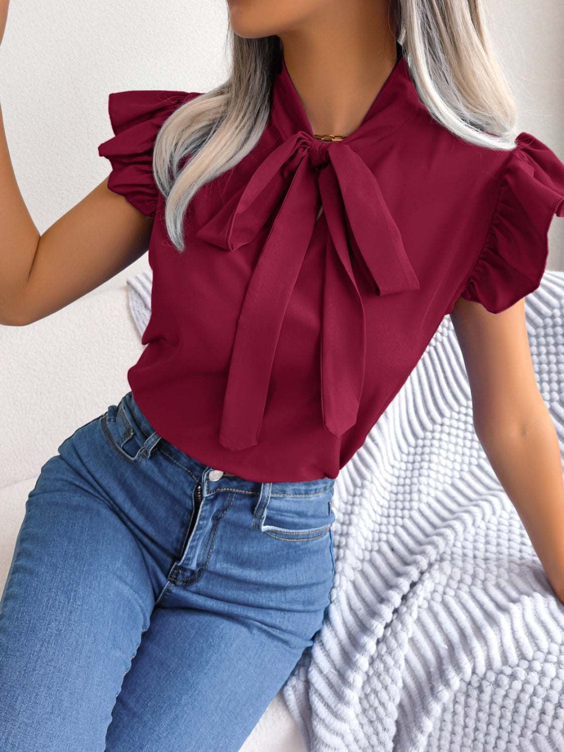 Tie neck cap sleeve blouse in red with a tied design and ruffled sleeves.