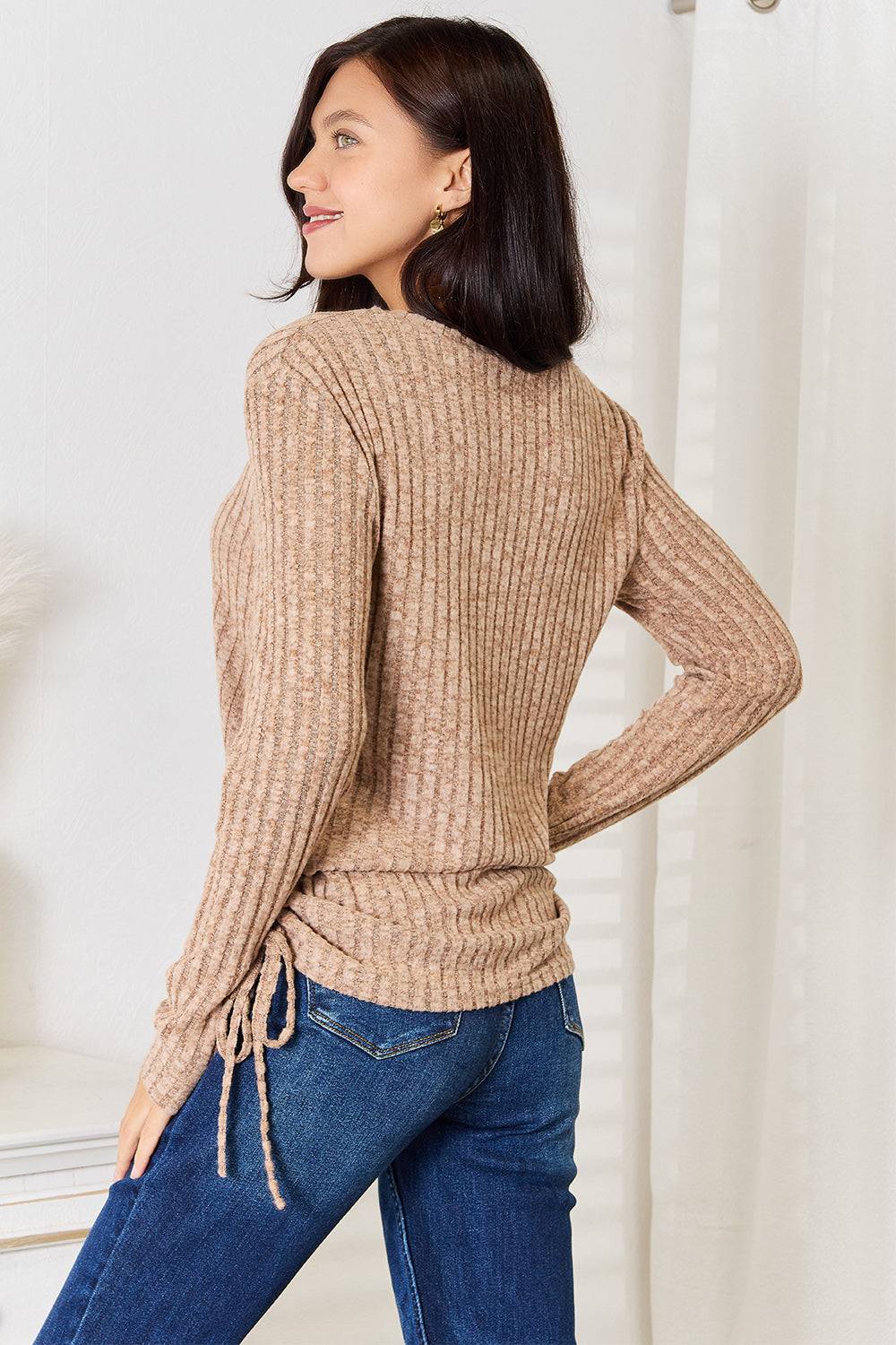 Woman wearing a beige drawstring ribbed long sleeve t-shirt with jeans.