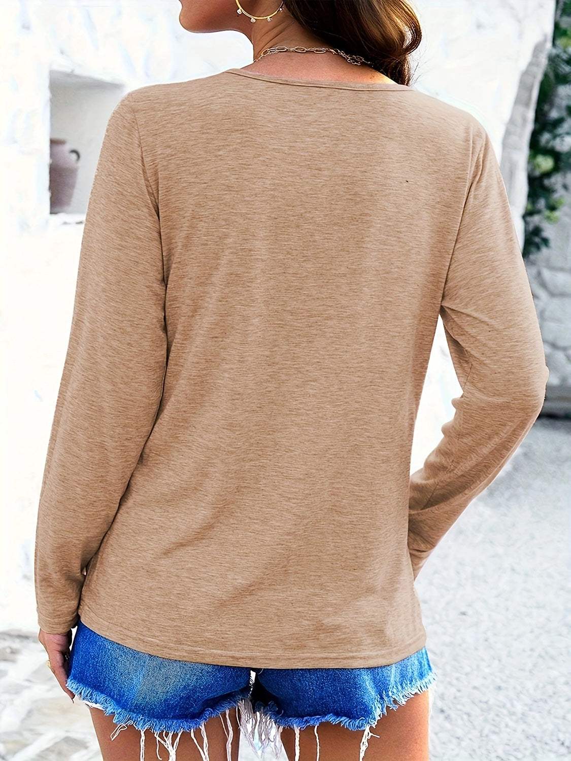 Back view of a beige crisscross V-neck long sleeve T-shirt paired with denim shorts.