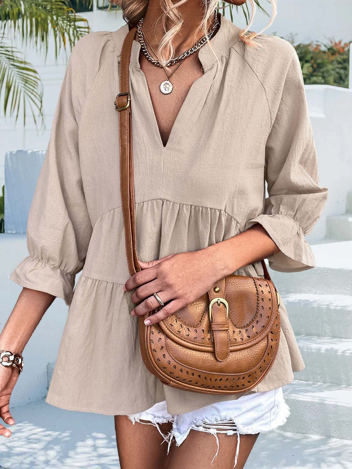 Ruffled notched three-quarter sleeve beige blouse with slight stretch and opaque fabric, styled with white shorts and a brown leather crossbody bag