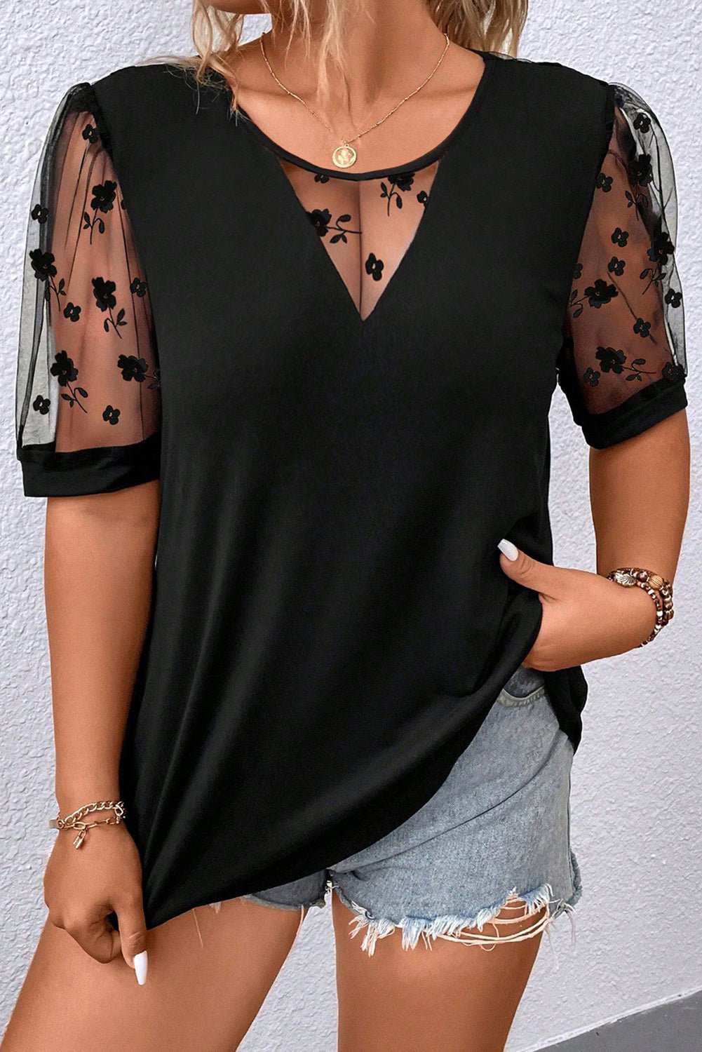 Plus size black V-neck T-shirt with floral mesh patchwork sleeves and front detail, styled with denim shorts.