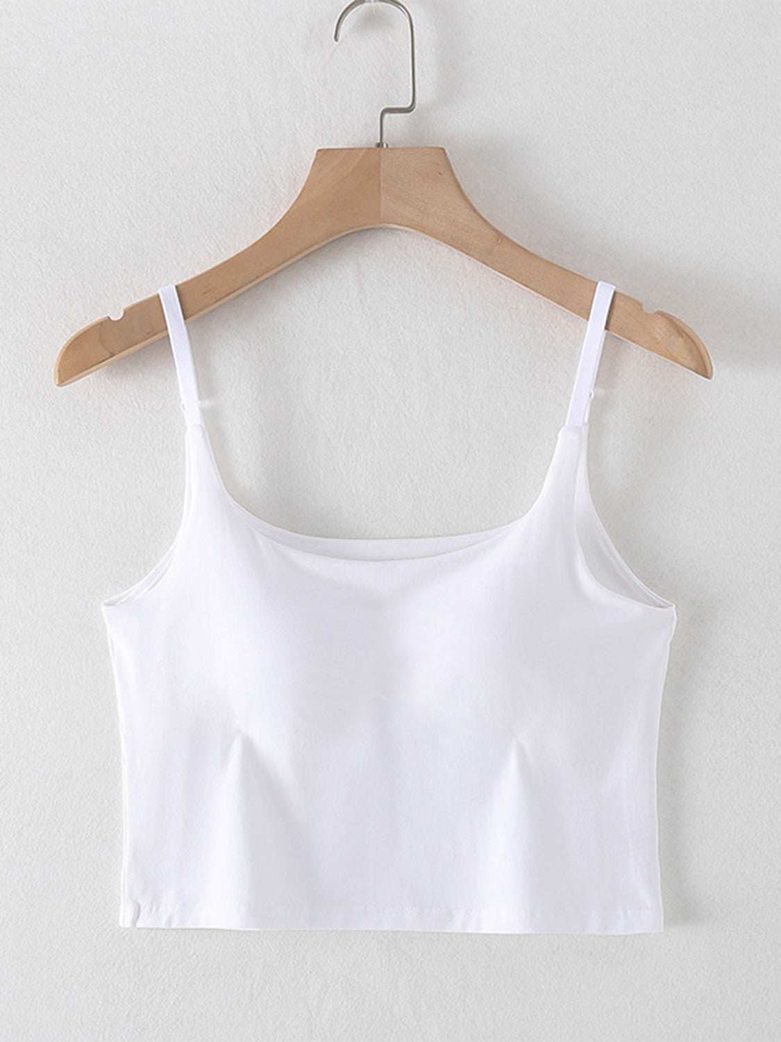 Scoop neck cropped cami with chest pads in white on a hanger.