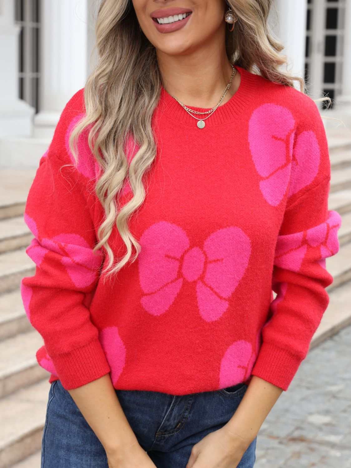 Red sweater with pink bow patterns, round neck, and dropped shoulder design.