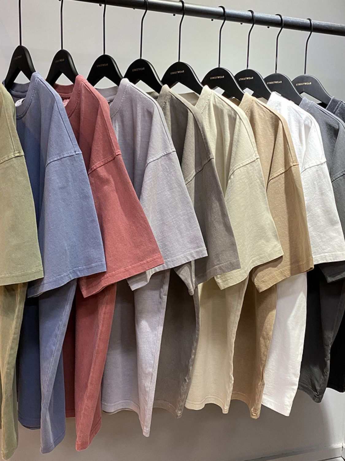 Men's round neck short sleeve t-shirts in assorted colors hanging on a rack.