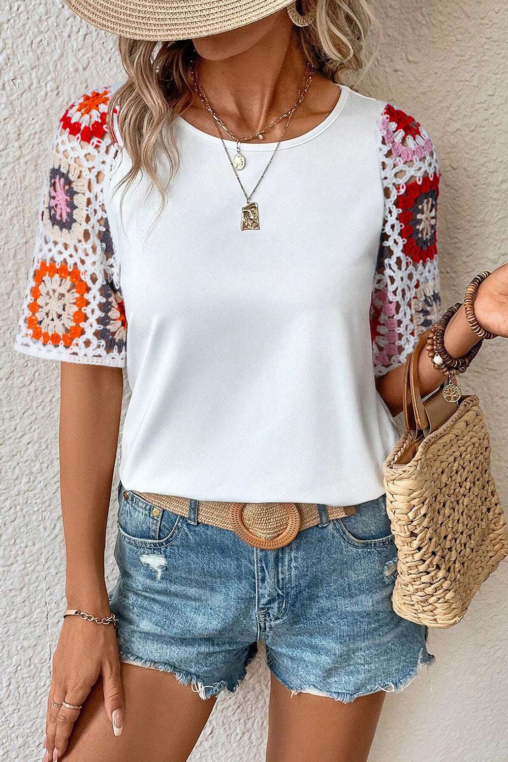 White geometric round neck short sleeve blouse with crochet patterned sleeves paired with denim shorts and woven handbag