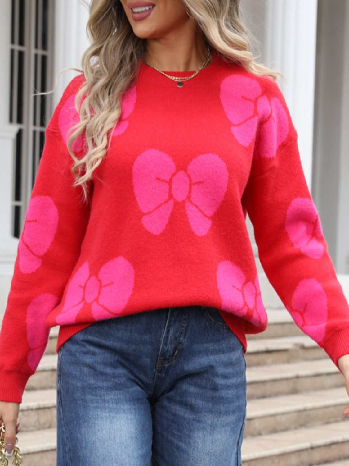 Angel Wings Bow Round Neck Dropped Shoulder Sweater with pink bow patterns on red fabric.