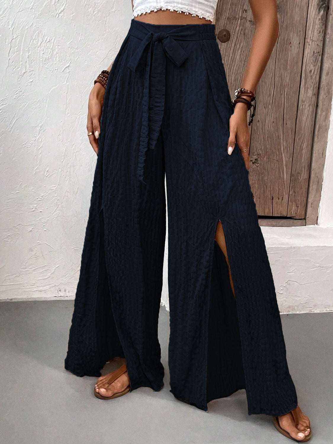 Wide leg black pants with slits and tie detail, worn by a model.