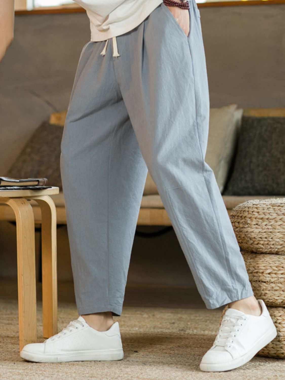 Plus size drawstring pants with pockets in light gray, featuring a relaxed fit and white sneakers.
