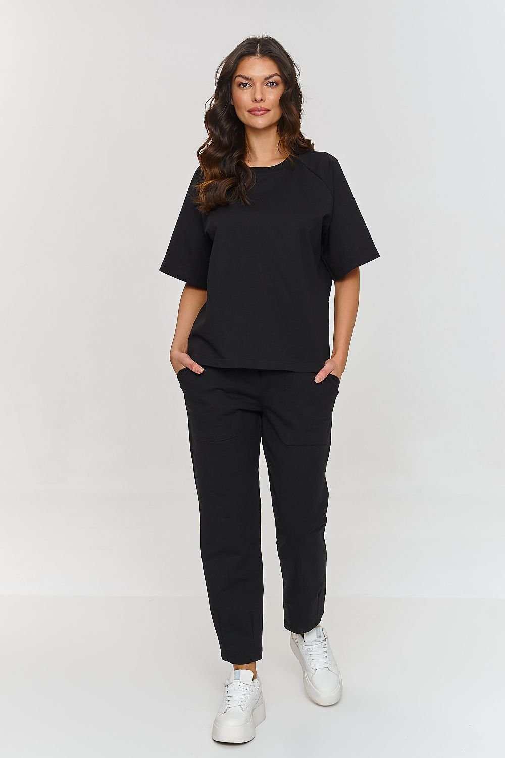 Woman wearing Set Makadamia black cotton tracksuit with loose top and straight-leg pants.