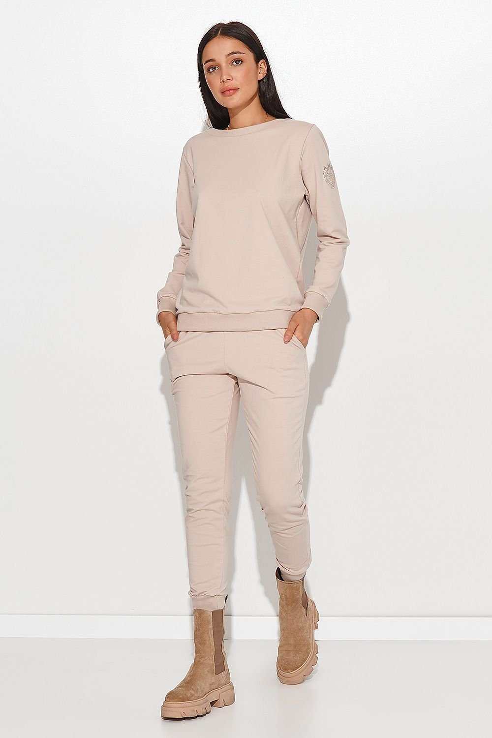 Woman wearing beige Set Numinou cotton knitwear with round neckline blouse and slim pants with side pockets.