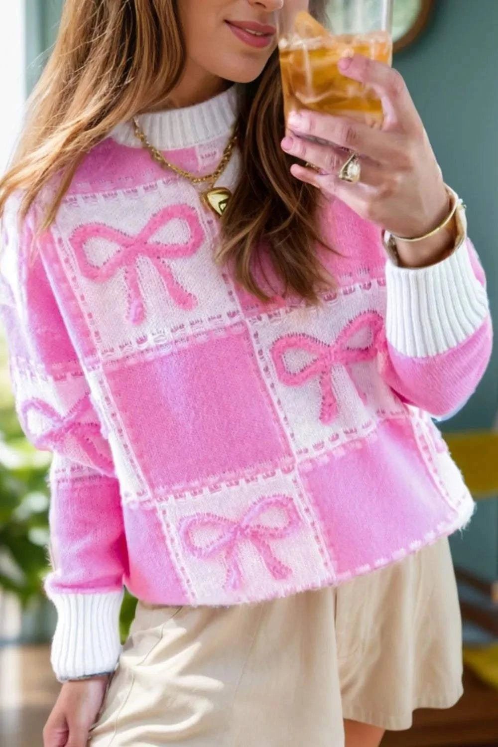 Pink bow round neck long sleeve sweater with white cuffs and hem, featuring a checkered pattern and bows design.