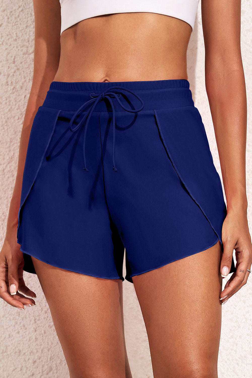Women's navy blue drawstring waist swim shorts made of stretchy nylon and spandex, perfect for the beach.