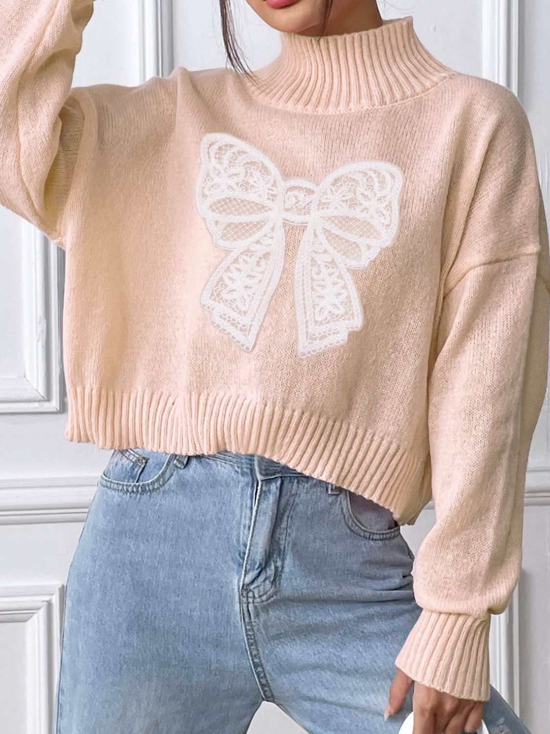 Bow Turtleneck Long Sleeve Sweater in beige with white bow design, slightly stretchy polyester material.