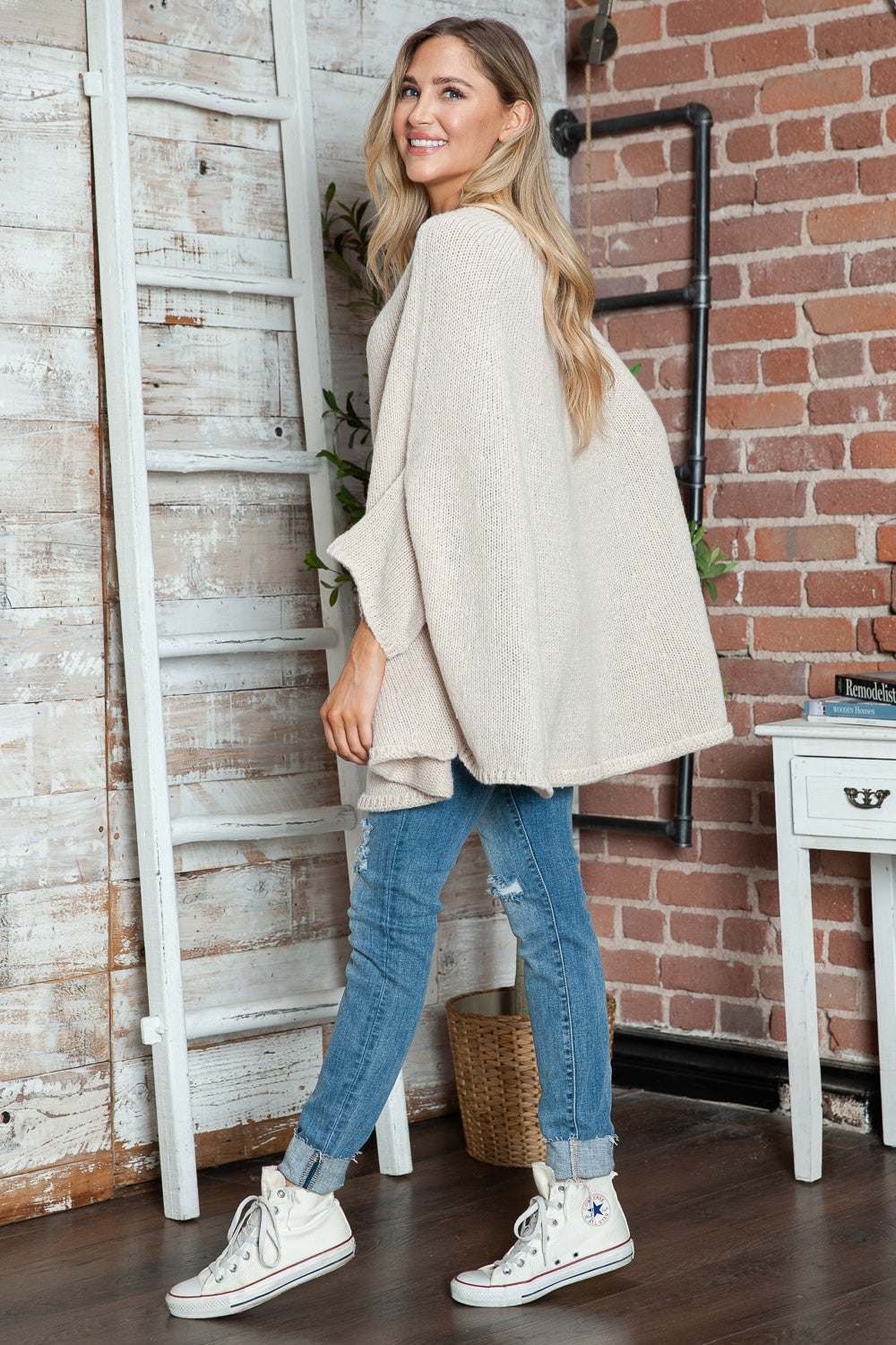 Round neck batwing sleeve sweater in beige, styled with blue jeans and white sneakers.