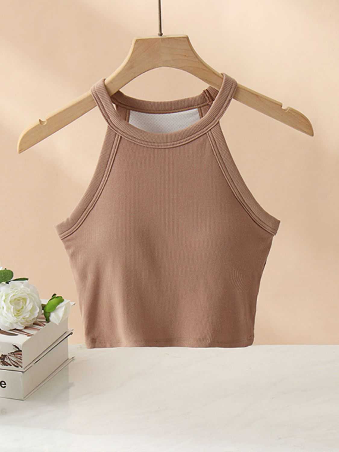 Ribbed Grecian neck cropped tank with chest pads on hanger.