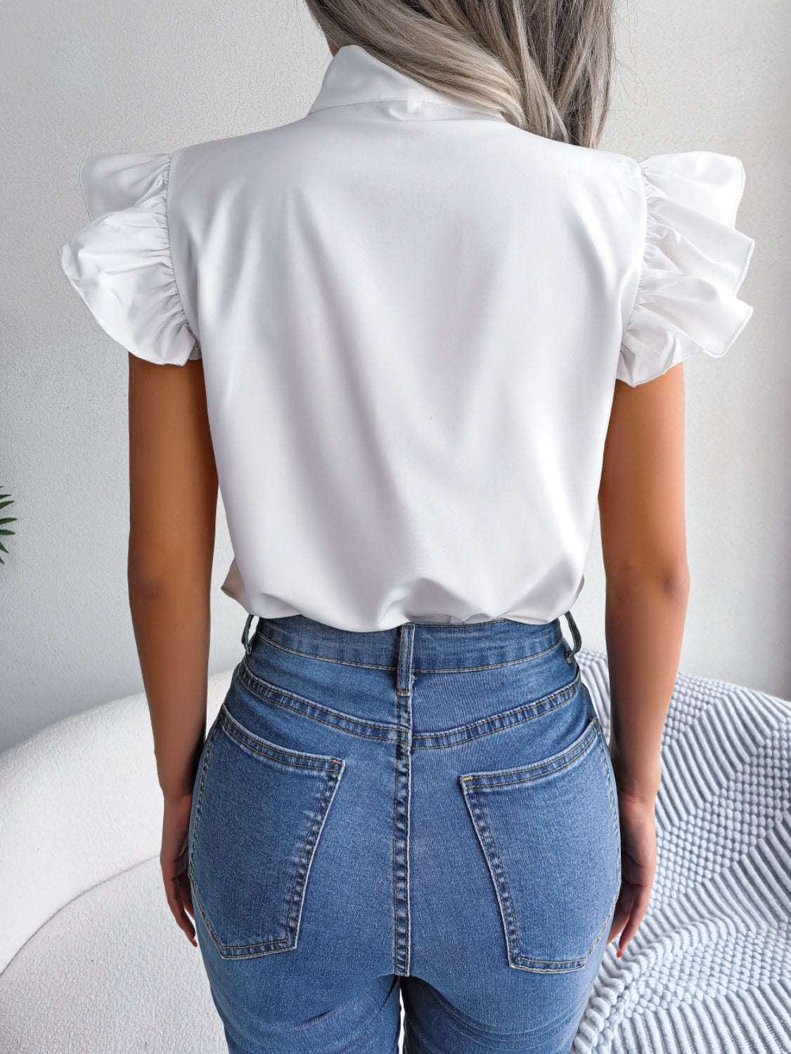 Tie neck cap sleeve blouse with ruffled sleeves in white.