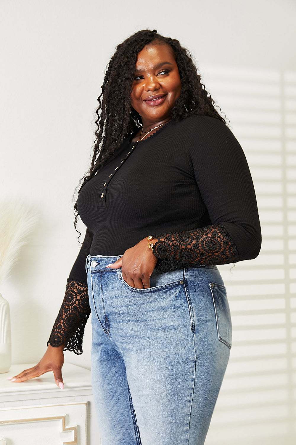 Plus size woman wearing a black crochet lace hem sleeve button top with blue jeans.