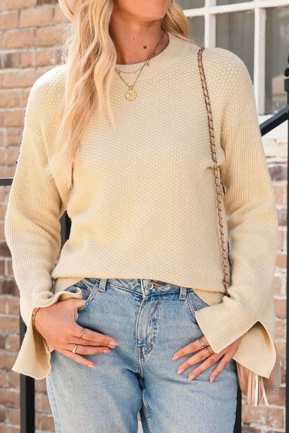 Textured round neck long sleeve sweater with slit and slightly stretchy fabric.
