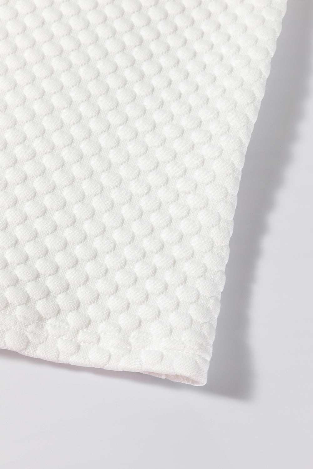 Textured round neck puff sleeve blouse fabric close-up.